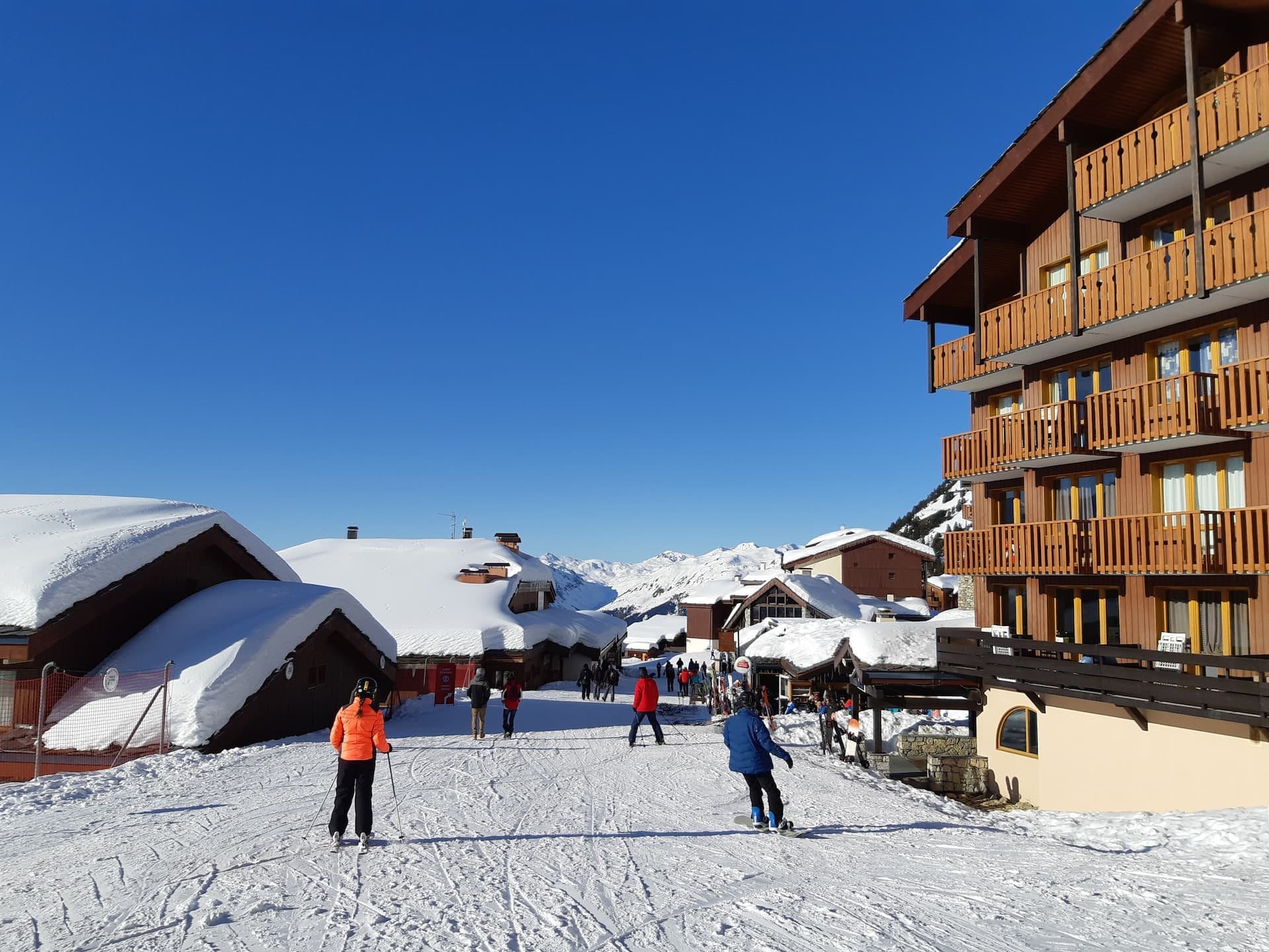 Des skieurs devant la résidence Les Néréïdes, sur la piste qui longe le bâtiment