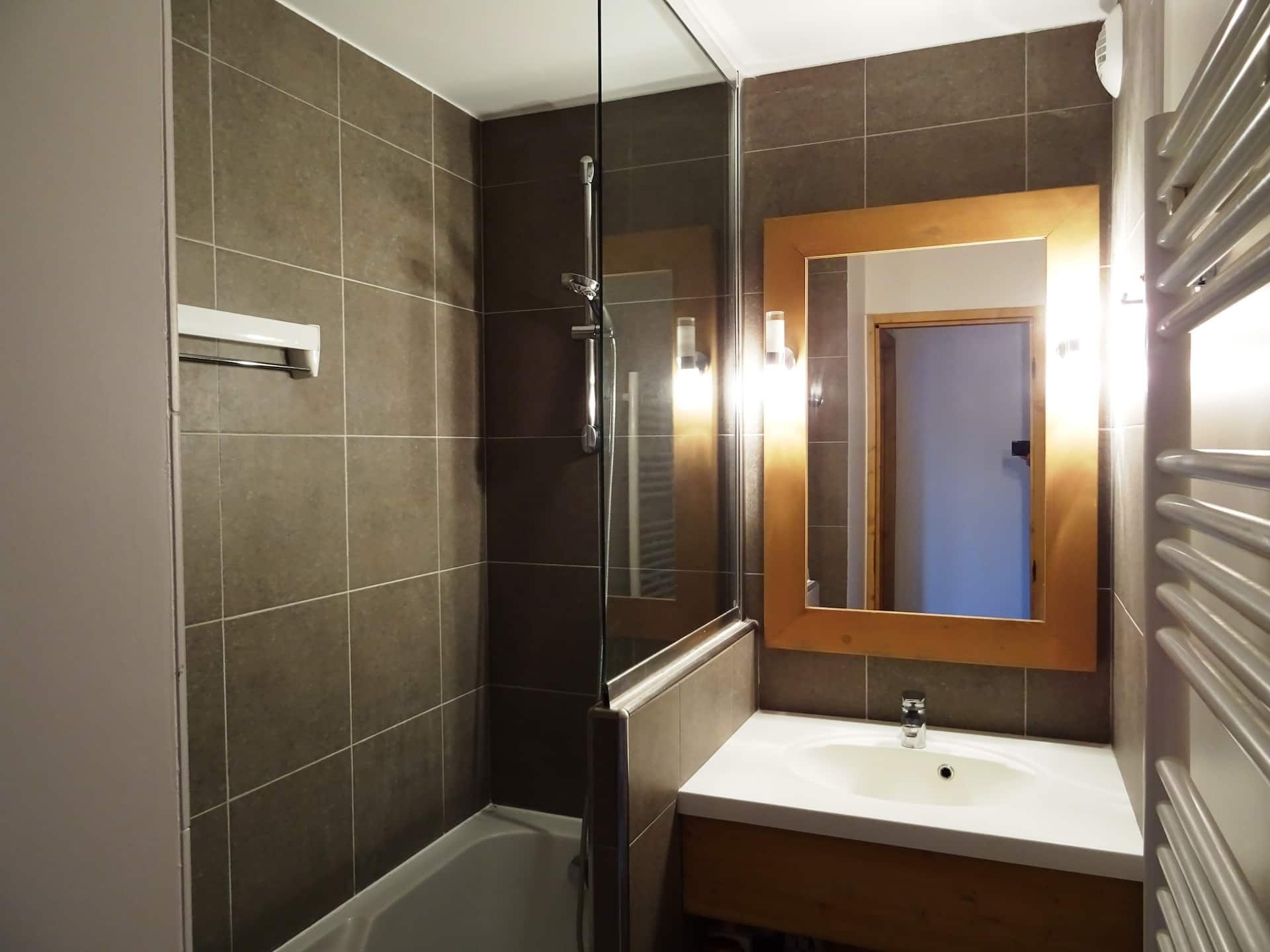 Salle de bain avec baignoire, lavabo et grand miroir