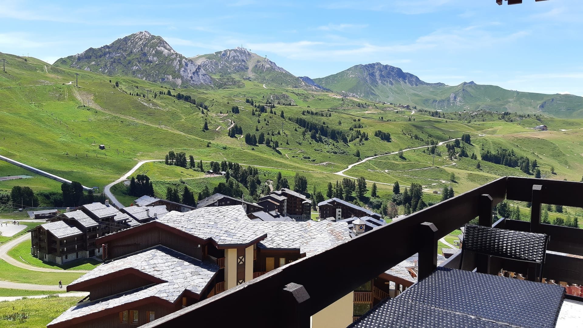 La vue depuis le balcon de l'appartement en été, alpages verts et sentiers au-dessus de Belle-Plagne